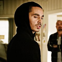 a man in a black hoodie standing next to another man