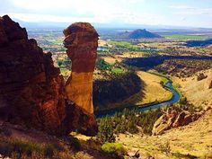 the valley is surrounded by large rocks and green fields with trees on both sides, along with mountains in the distance