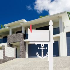 a house with a white anchor sign in front of it and a blue sky background