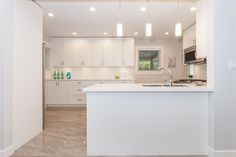 an empty kitchen with white cabinets and counter tops