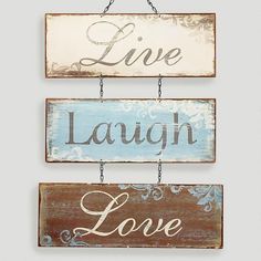 three wooden signs hanging on a wall above a table with candles and vases next to it