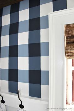 a bathroom with blue and white checkered wallpaper on the walls next to a window