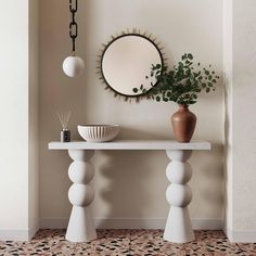 a white table with a mirror and vase on it next to a potted plant