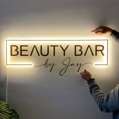 a woman holding up a sign that says beauty bar by jayy