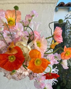 a vase filled with lots of colorful flowers next to a white wall and window sill