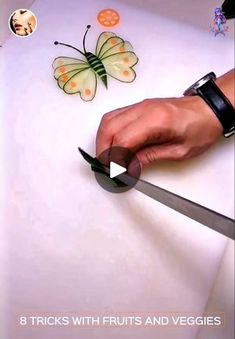 a person holding a knife in front of a cutting board with butterflies on the table