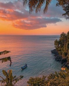 the sun is setting over the ocean with boats in the water and palm trees on the shore