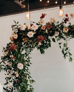 an arrangement of flowers and greenery hanging from the ceiling