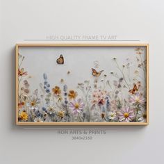 an art piece with flowers and butterflies on it, mounted in a wooden frame against a white wall