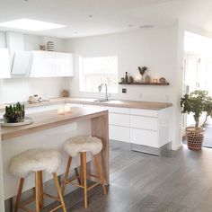 two stools are in front of the kitchen counter and bar with plants on it