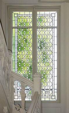 the stairs lead up to a stained glass window in an old building with white railings