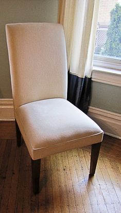 a white chair sitting on top of a hard wood floor next to a large window