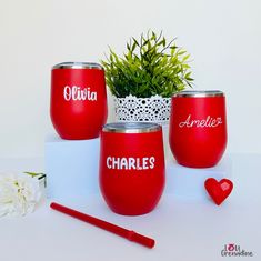 three wine glasses with names on them sitting next to a potted plant and pen