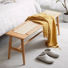 a wooden bench sitting on top of a white carpeted floor next to a bed