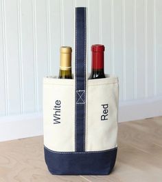 two bottles of wine in a tote bag on a wooden floor next to a white wall