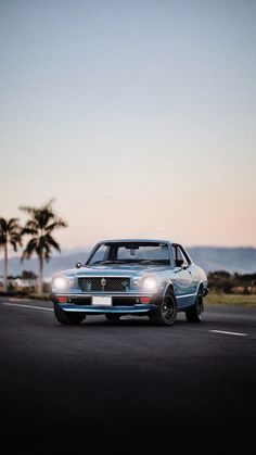 a car driving down the road with palm trees in the background