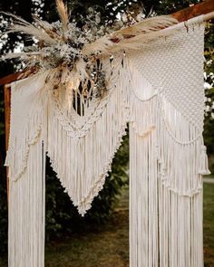 an outdoor wedding ceremony with macrami and feathers