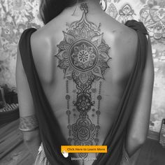 the back of a woman's body with an intricate tattoo on her upper back