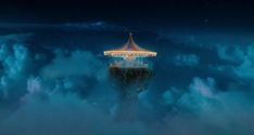 a merry go round in the middle of clouds at night with lights on it's top