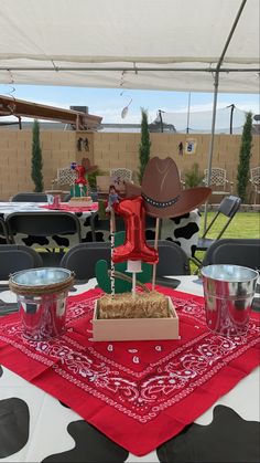 a table topped with a cake covered in straw and cowboy hats on top of it