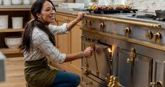 a woman kneeling down to pick something up from an oven in a kitchen that is being used for cooking