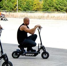 a man sitting on an electric scooter and another person standing next to him