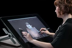 a woman is drawing on the screen of her laptop