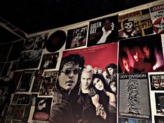 a wall covered with posters and pictures of the band's main members, including one man