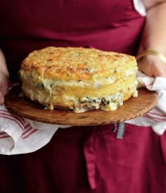 a person in an apron holding a plate with food on it and wearing a red apron