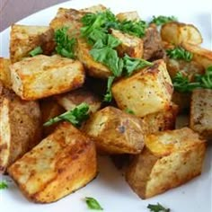 a white plate topped with cooked potatoes and parsley