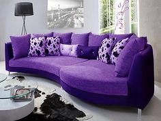 a living room with purple couches and cow hide rugs on the floor in front of a large window