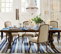 a dining room table with chairs and a blue striped rug on the floor in front of it