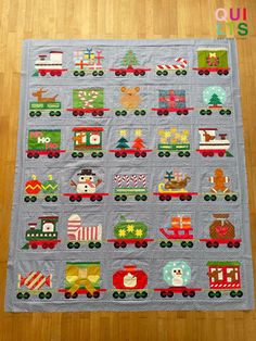 a quilted christmas train themed wall hanging on a wooden floor next to a wood floor