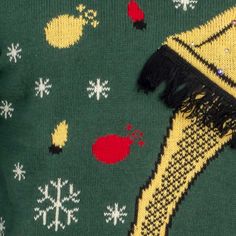 a green sweater with yellow and red snowflakes on it, featuring a tasseled neckline