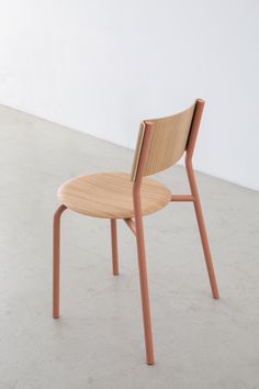 a wooden chair sitting on top of a cement floor next to a white wall in an empty room