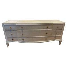 a white and silver dresser with brass knobs on the top, against a white background