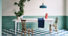 a dining table with two chairs and a potted plant on the top, in front of a checkered wall