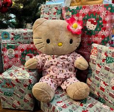 a hello kitty stuffed animal sitting in a chair with christmas presents behind it on the floor