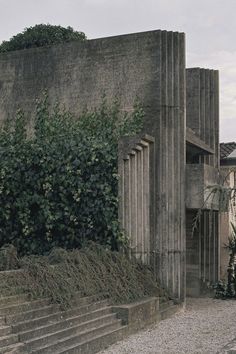 an old building with steps leading up to it and plants growing on the side wall