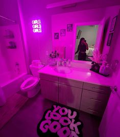 a woman taking a selfie in a bathroom with pink lighting on the walls and floor