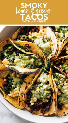 a white plate topped with tacos covered in guacamole