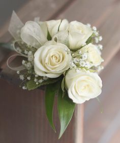 a bouquet of white roses and baby's breath on a wooden box with greenery