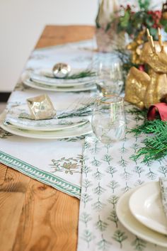 the table is set for christmas dinner with gold and green decorations