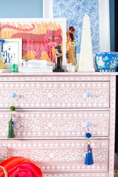 a pink dresser with blue and white wallpaper