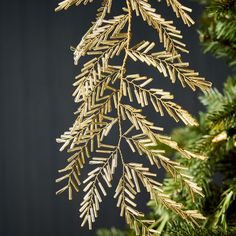 a close up view of the branches of a christmas tree with gold needles on it