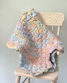 a crocheted blanket sitting on top of a wooden chair