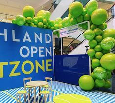 an open store with tables and chairs in front of green fruit hanging from the ceiling