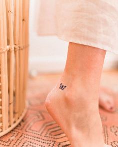 a small butterfly tattoo on the foot of a woman's right leg, next to a wicker basket