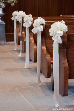 the aisle is lined with white flowers and pews