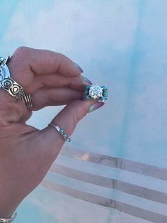 a woman's hand holding two rings with different designs on them and one ring has an owl